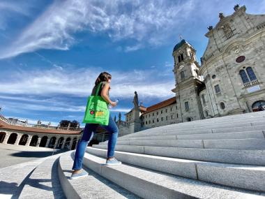 Eine Frau unterwegs auf dem FoodTrail auf der Treppe vor dem Kloster Einsiedeln. 